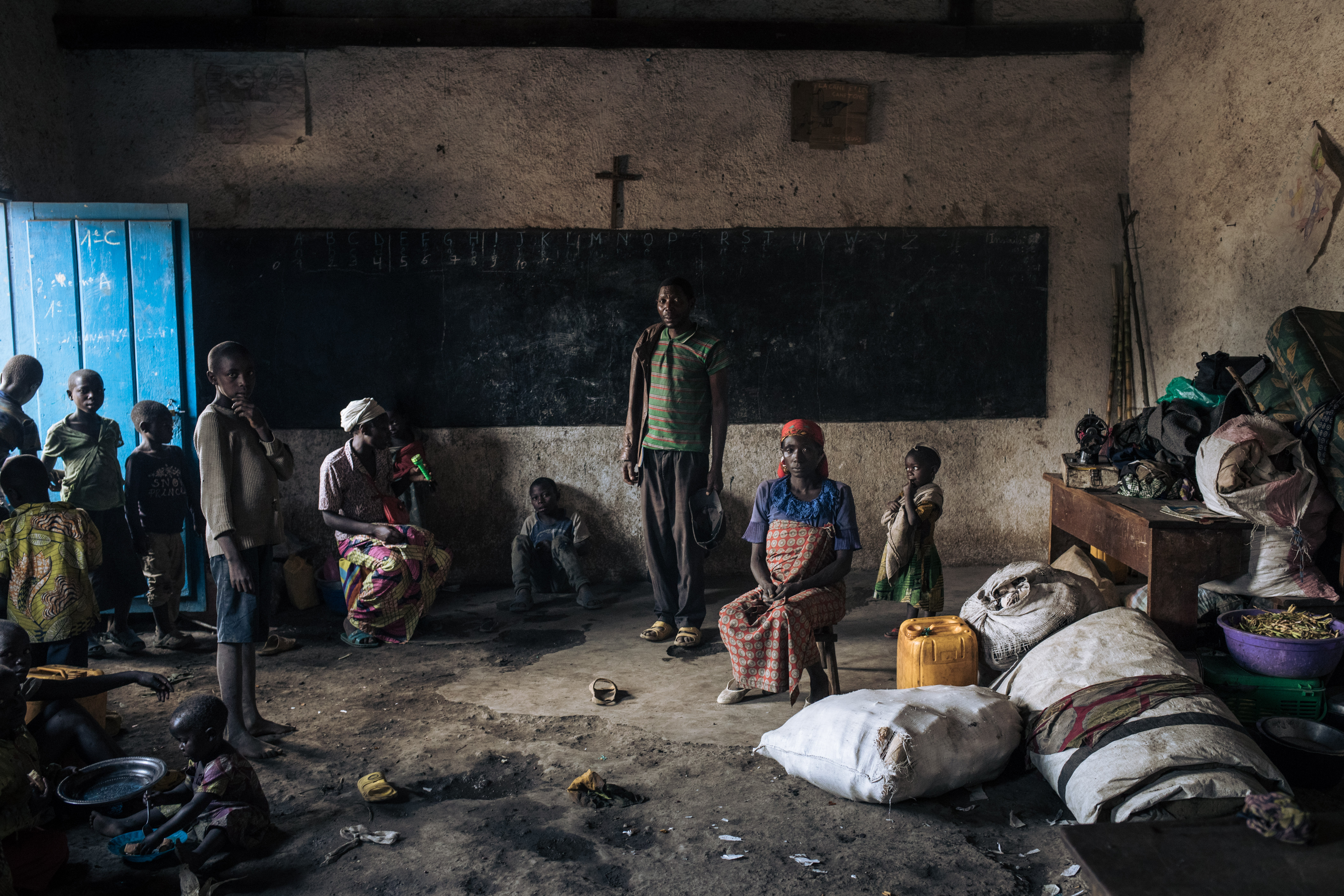 Displaced people, including children, stand in the classroom of Rumangabo elementary school