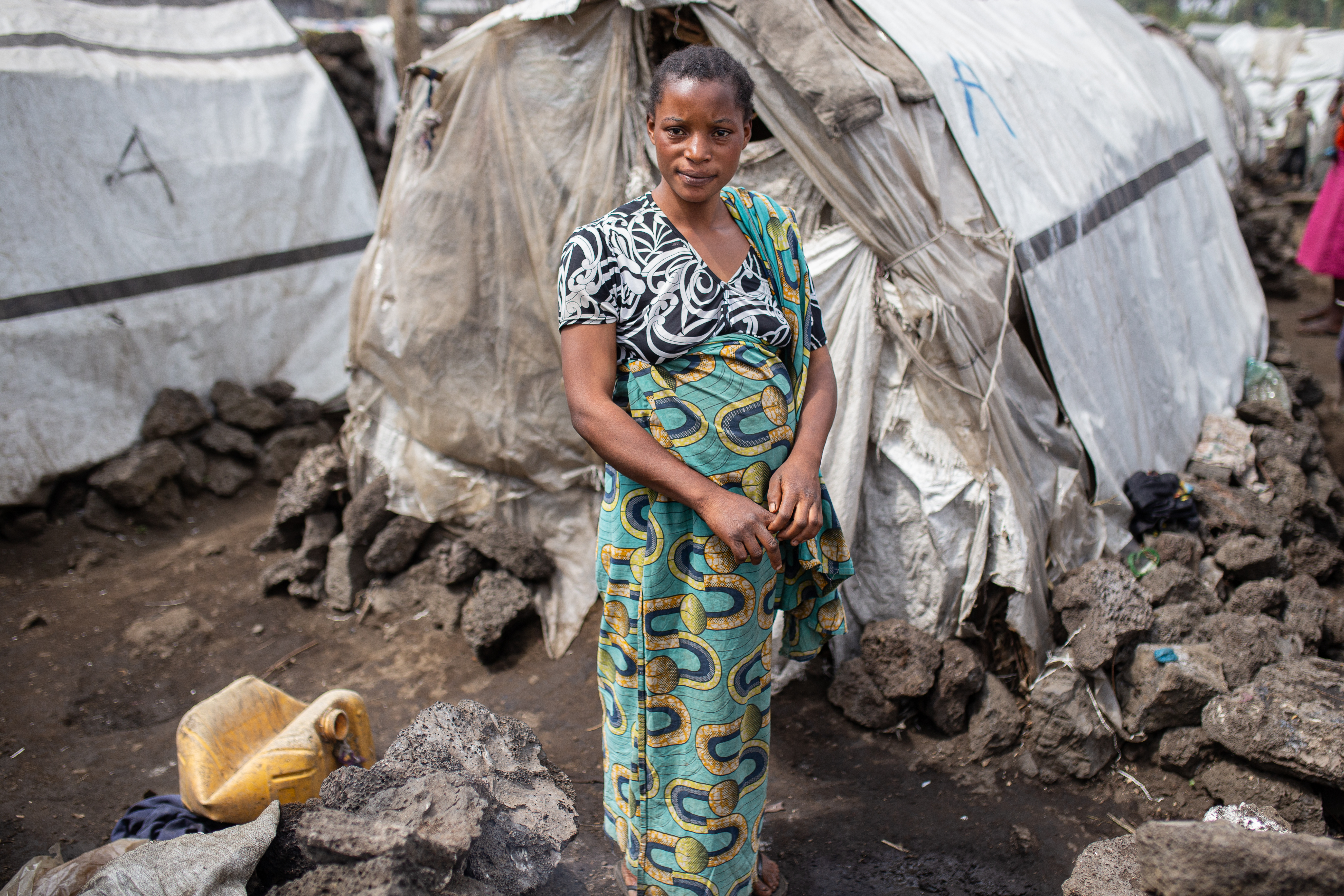 Asifiwe Seburo, who is seven-months' pregnant, stands outside a makeshift shelter