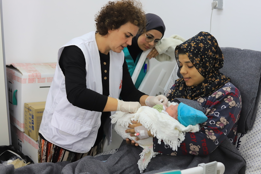  MSF medical staff discussing with patient and checking on newborn child in the Emirati hospital, Rafah, southern Gaza.
