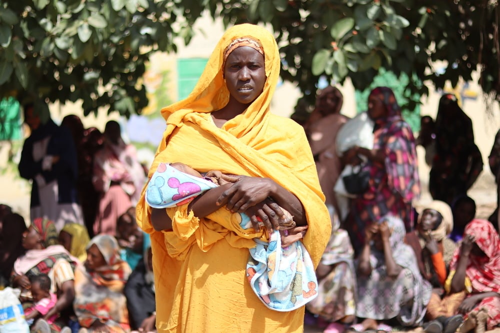 Woman waits with baby for food parcel