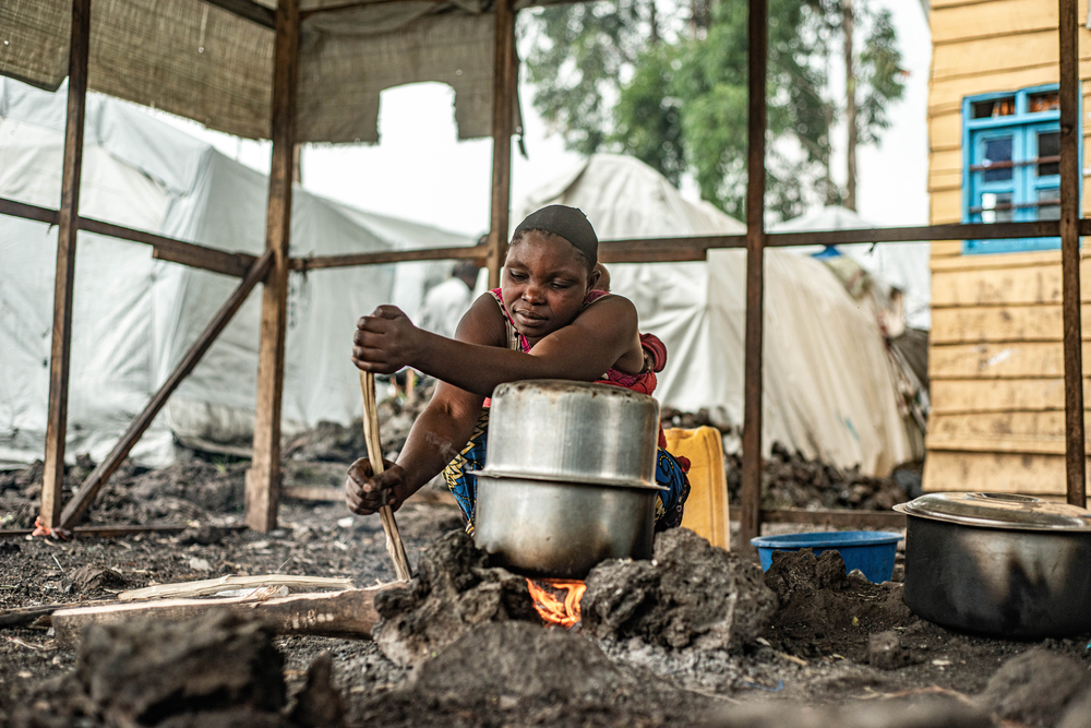 Woman prepares food over fire